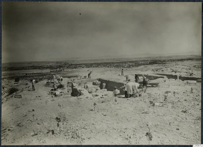 Workers excavating walls on the acropolis at Idalion, with a wide plain and town below.