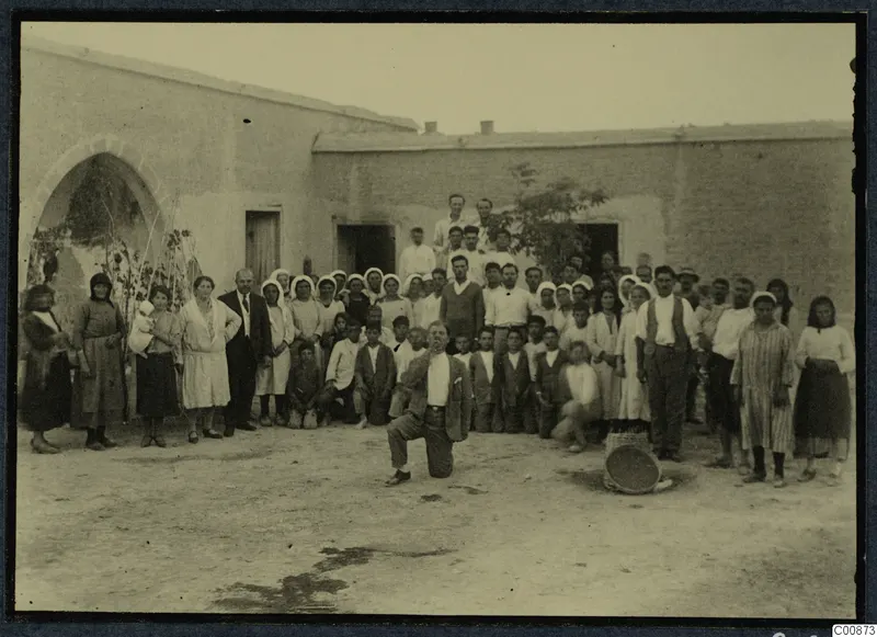 Farewell party: a large group of people posed in a dusty courtyard in front of a whitewashed building at Idalion.