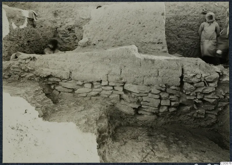 Excavation at Idalion Acropolis: a thick earthen brick wall rests on a low course of flat stones in a trench