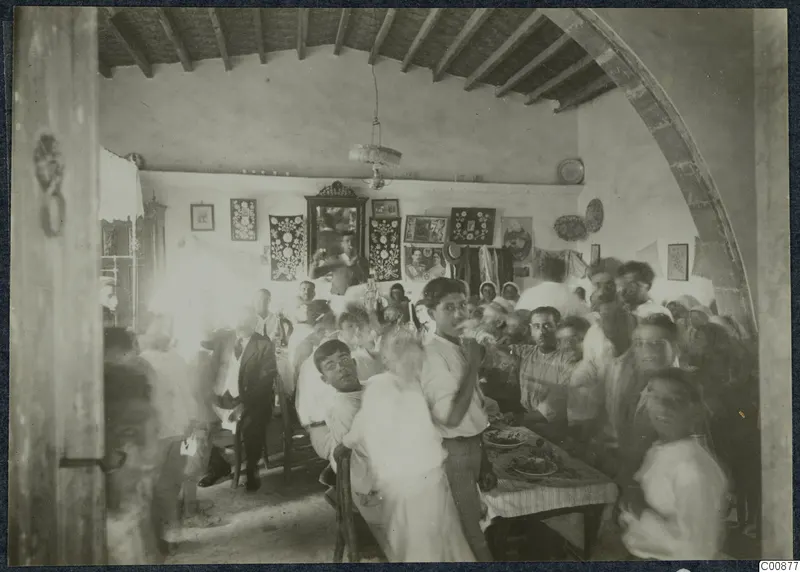 Farewell party in a vaulted room at Idalion, with people crowded around a table laid with food