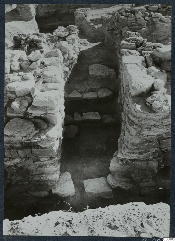 Excavated trench at Idalion Acropolis with stone walls and flat stones lying on its floor and ledges