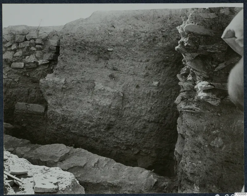 Excavation at Idalion Acropolis showing a trench with a tall earthen section and stone walling