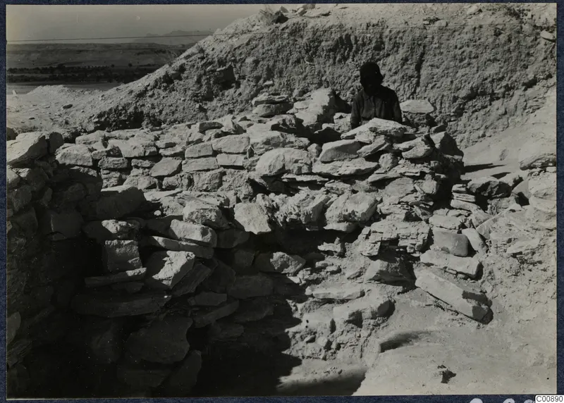 Excavation at Idalion Acropolis with rough stone walls and a person standing behind them.