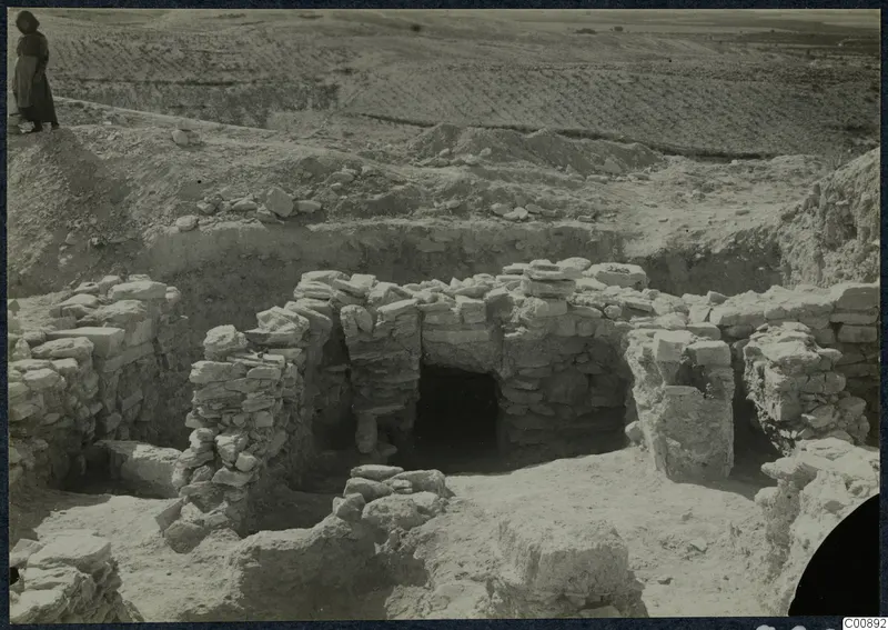 Excavated stone walls at Idalion Acropolis, with a standing person on the edge of the excavation at upper left.