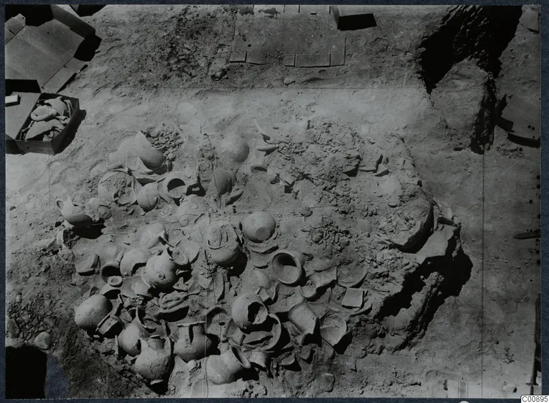 Pottery vessels and broken sherds lying in excavated soil at Idalion Acropolis, seen from above.