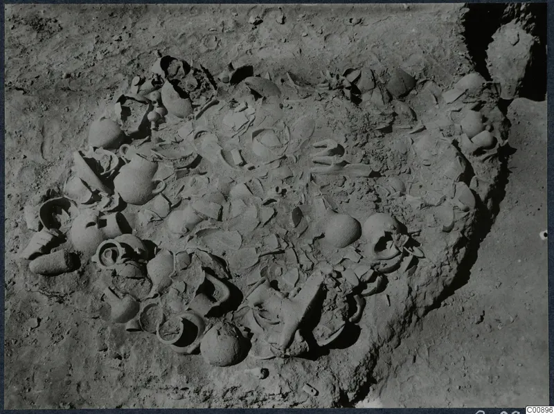 Excavated hollow at Idalion Acropolis with many broken and whole pottery vessels lying in the soil