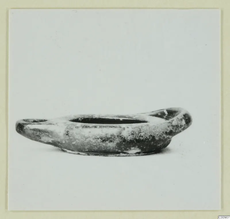 Oil lamp of black-glazed pottery, shown in side view against a plain background