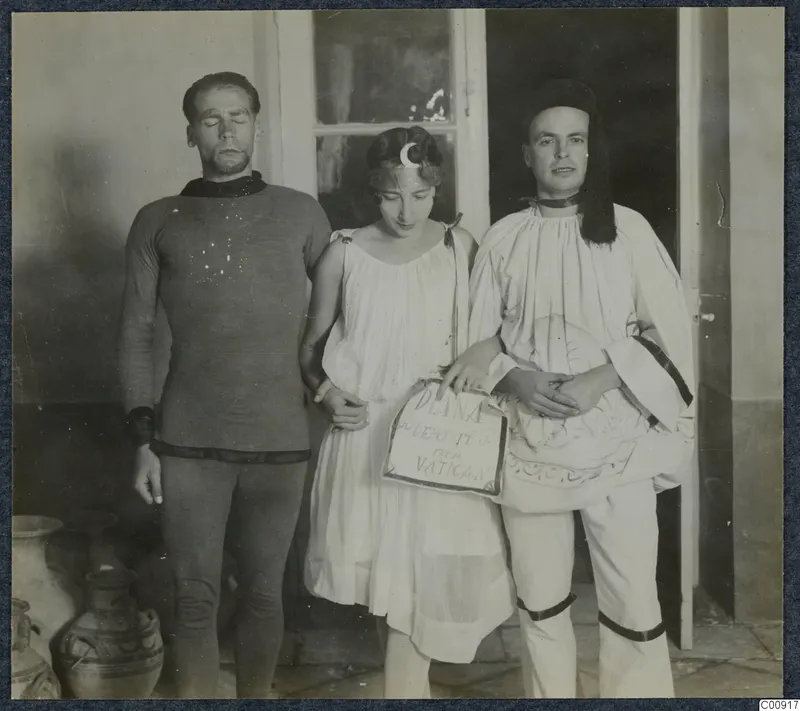 Three people in costume posing in a doorway at a masquerade, with large pottery vessels at the left edge.