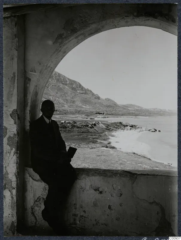 John Lindros seated in an arched vault of Lambousa monastery, with the sea and hills visible through the opening