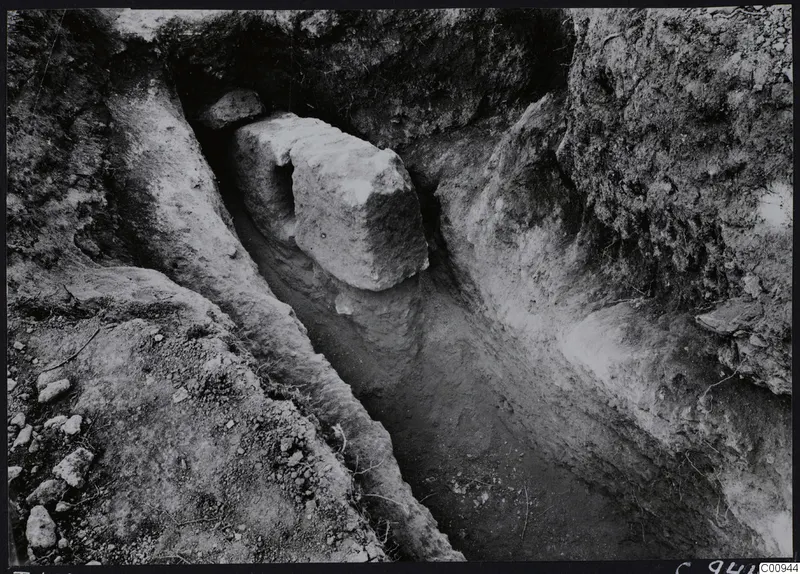 Tomb 422 at Lapithos Kastros during excavation, showing a narrow cut with a large stone block