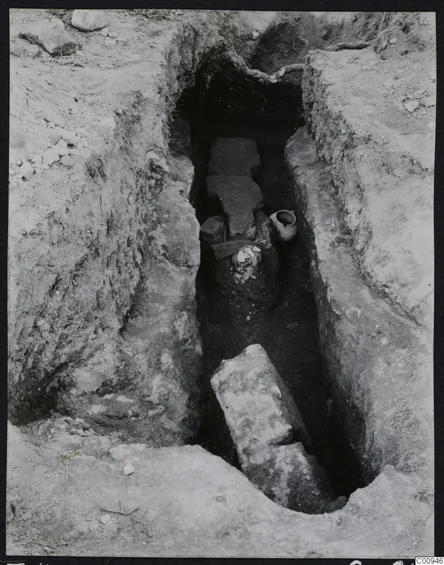 Tomb 422 at Lapithos Kastros during excavation, with flat stone slabs and pottery in the tomb chamber.