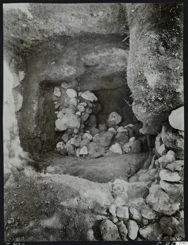 Excavated tomb chamber at Lapithos, its opening filled with heaped and stacked stones