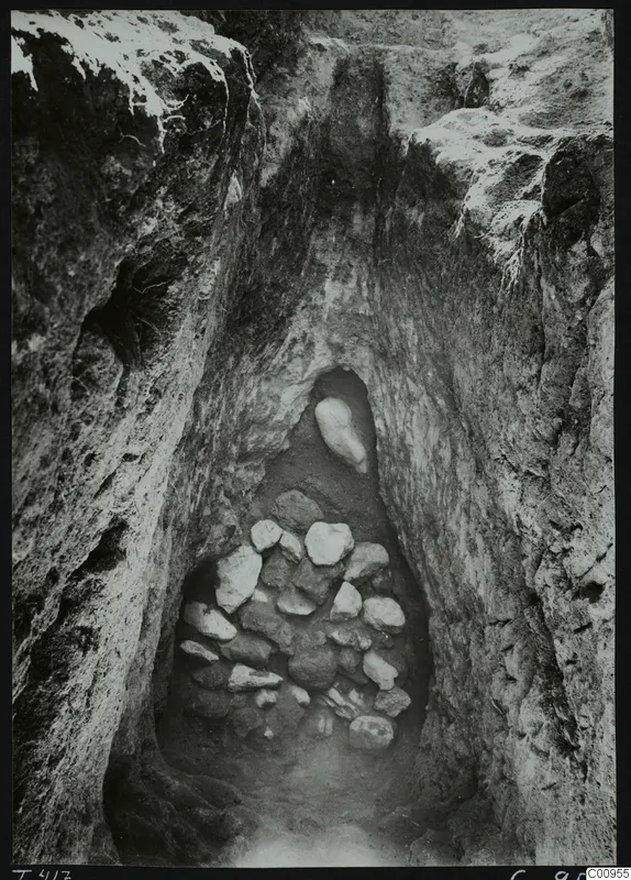 Tomb 417 at Lapithos Kastros: a sloping dromos cut into the ground, with a heap of stones at its far end.