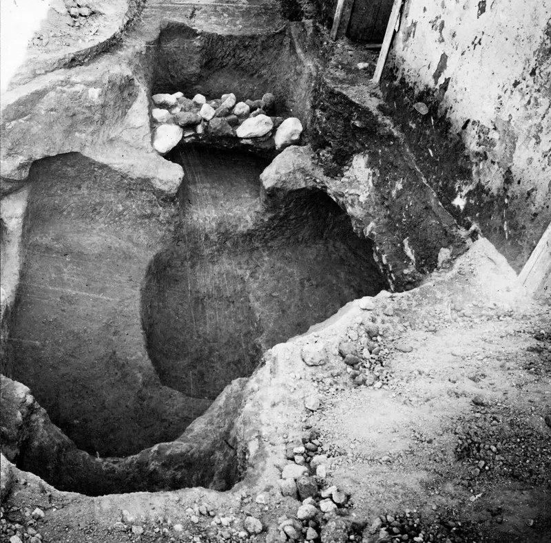 Tomb 501 at Lapithos, a rock-cut tomb opening in excavated ground with stones at its back.