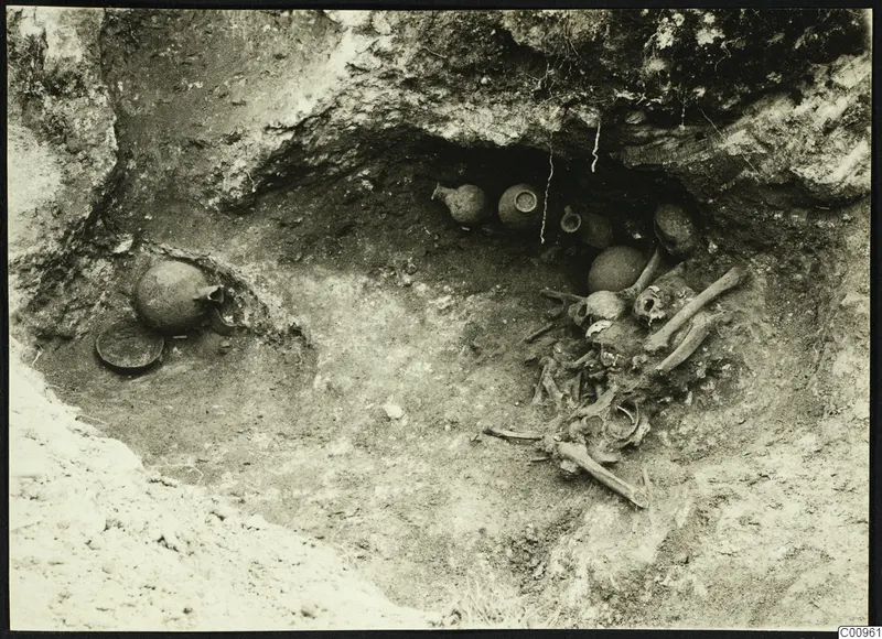 Kylistra tomb at Lapithos during excavation, with pottery vessels in the niche and a skeleton beside them