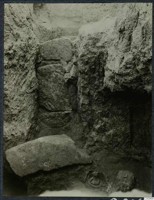 Excavation trench at Idalion with large stone blocks and an object lying in the soil at the bottom