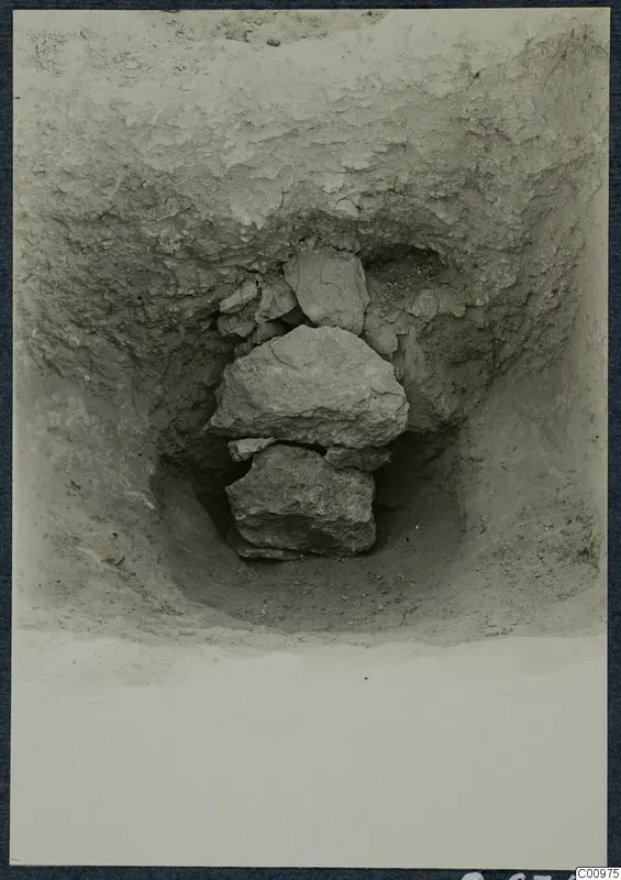 Excavation pit at Idalion with a stack of large stones lying in the soil.