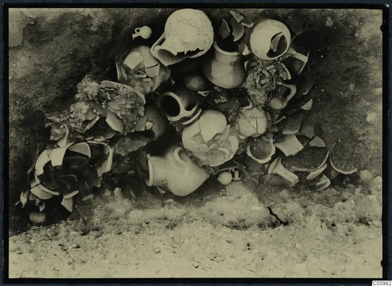 Pottery vessels and sherds lying in situ in a dark excavated hollow at Idalion Acropolis.