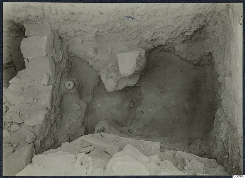 Excavation trench at Idalion Acropolis with pale stone blocks and round objects lying in the soil.