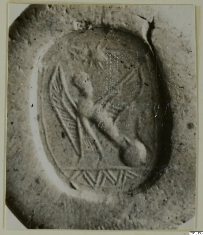Engraved oval stone seal with a winged creature and a hatched band below it, shown close up