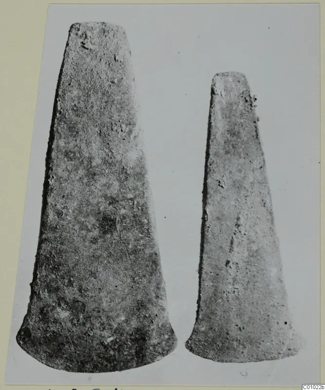 Two tapering metal axe blades photographed side by side, from Lapithos