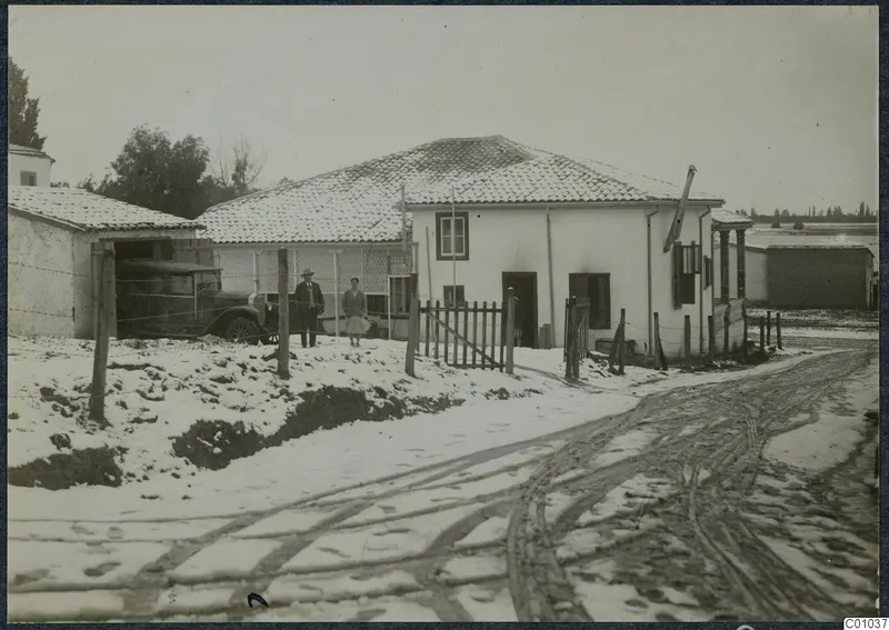The Swedish house in snow, Nicosia, with a parked car and two people standing by the wooden gate