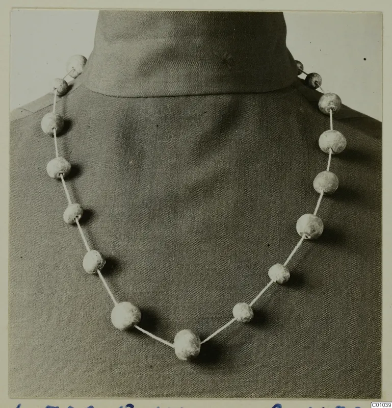 Necklace of pale faience beads strung on a cord, shown on a dressmaker's form at Lapithos.