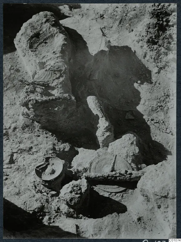 Excavation at Idalion Acropolis with large stones and objects lying in the dug soil.
