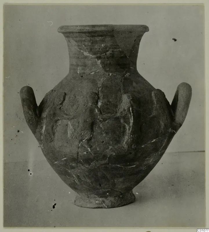 Two-handled jar with a flared rim and raised relief decoration on the body, photographed against a plain grey backdrop