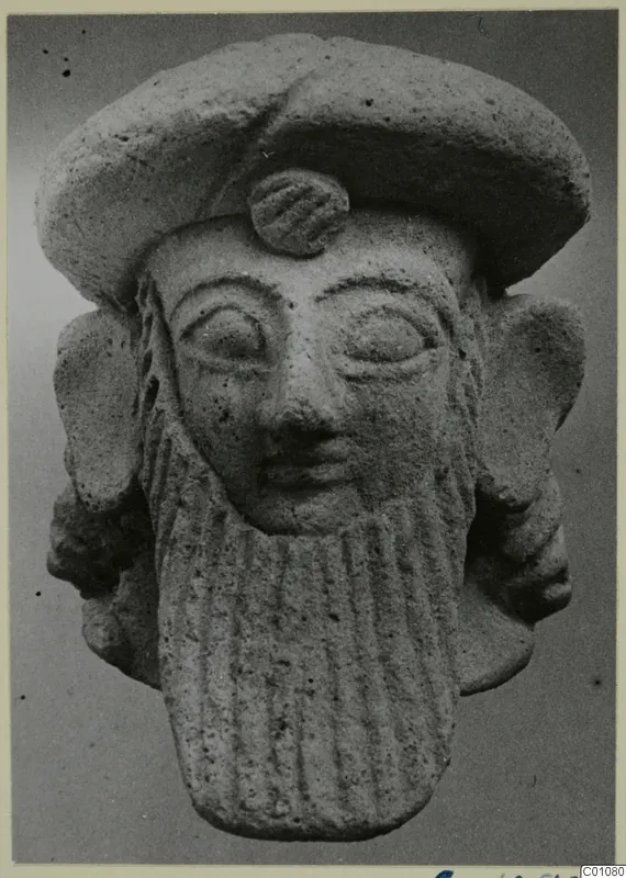 Terracotta Neo-Cypriote head with a flat cap, large ears and a long vertically ribbed beard, front view.