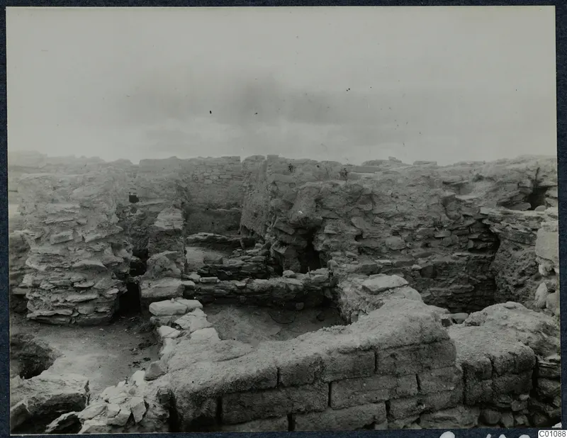 Excavated stone and mud-brick walls at Idalion Acropolis, with rubble and a small excavated room.