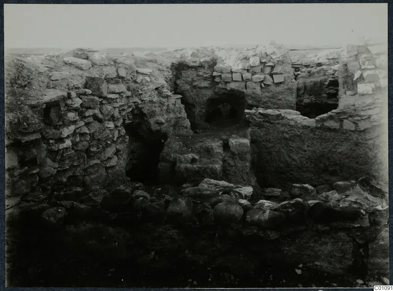Standing ruined stone walls with arched openings and fallen boulders at the Idalion acropolis during excavation