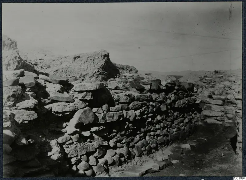 Excavated stone wall with large slabs and rubble at Idalion Acropolis, with an eroded earthen mass behind