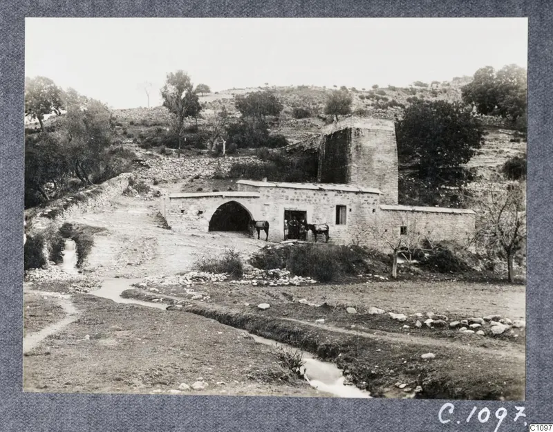 Copy photograph of the Old Mill at Kalavasos, a stone building with an arched opening and horses at its doorway.