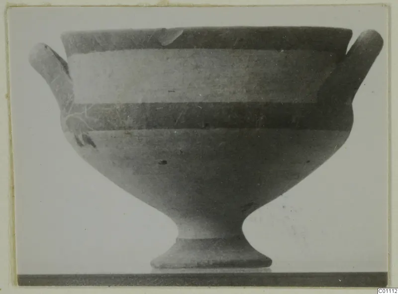 Pottery White Painted I bowl with two short side handles and a tall flared foot, seen in side view against a plain background.