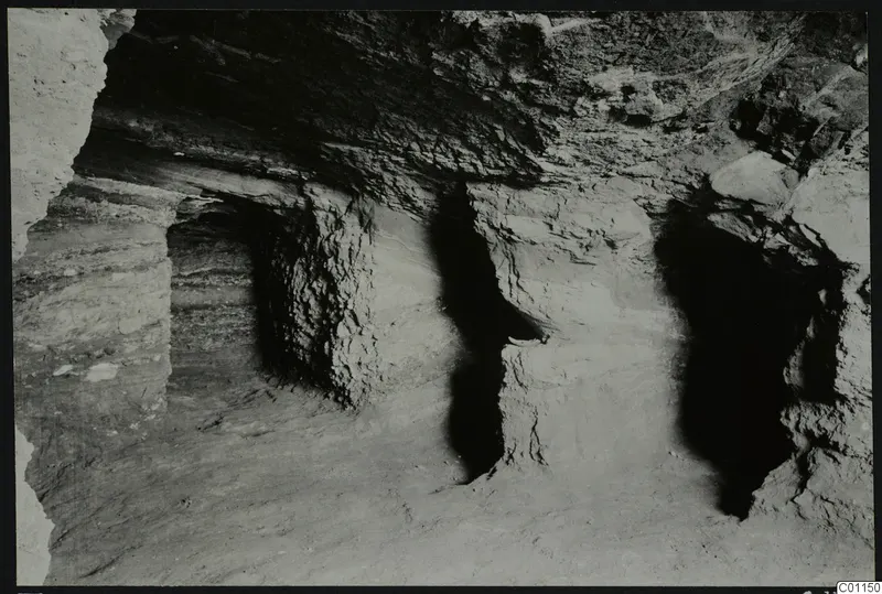 Interior of Tomb 2 at Marion during excavation, showing rock-cut walls and a loose soil floor
