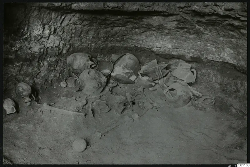 Tomb 10 at Marion with a cluster of pottery vessels and skeletal remains on the tomb floor