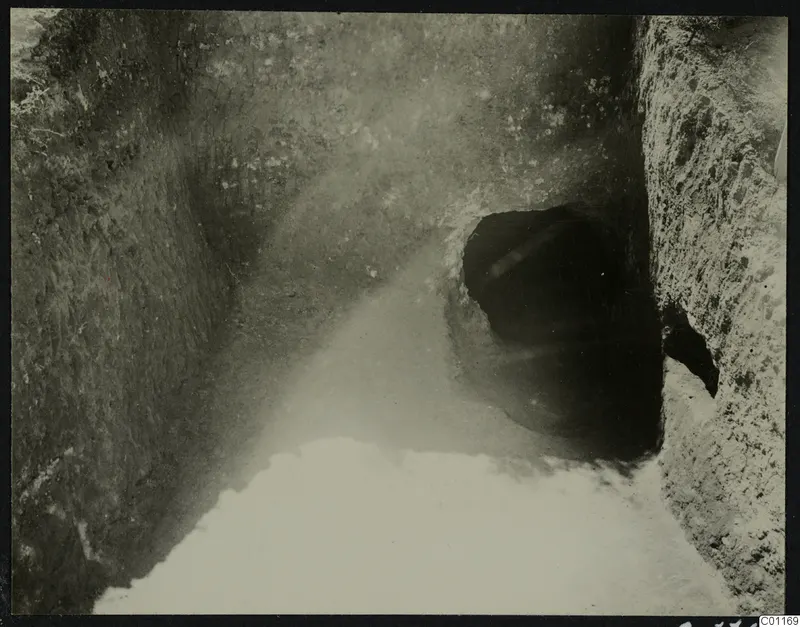 Sloping cutting at Marion leading to a dark tomb entrance, during excavation