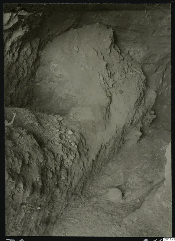Tomb 9 at Marion during excavation, with a rounded earth face and loose stones on the slope