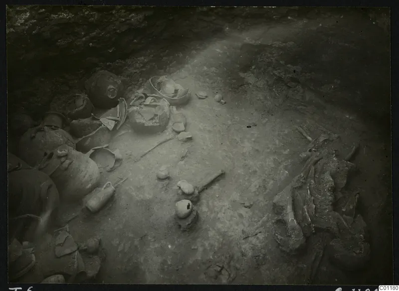 Tomb 6 at Marion during excavation, with broken pots and a skeleton on the floor of the chamber