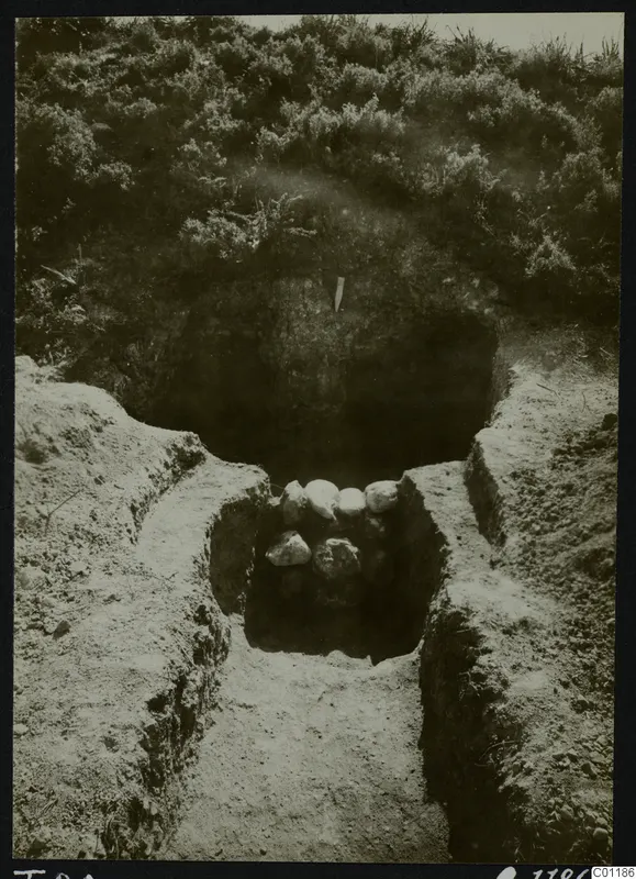Tomb 20 at Marion during excavation, with a dug dromos leading to a cavity and a cluster of pale stones.
