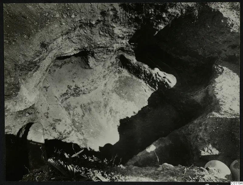 Tomb 14 at Marion during excavation, showing the rock-cut cavity with stones and rounded objects at the edge
