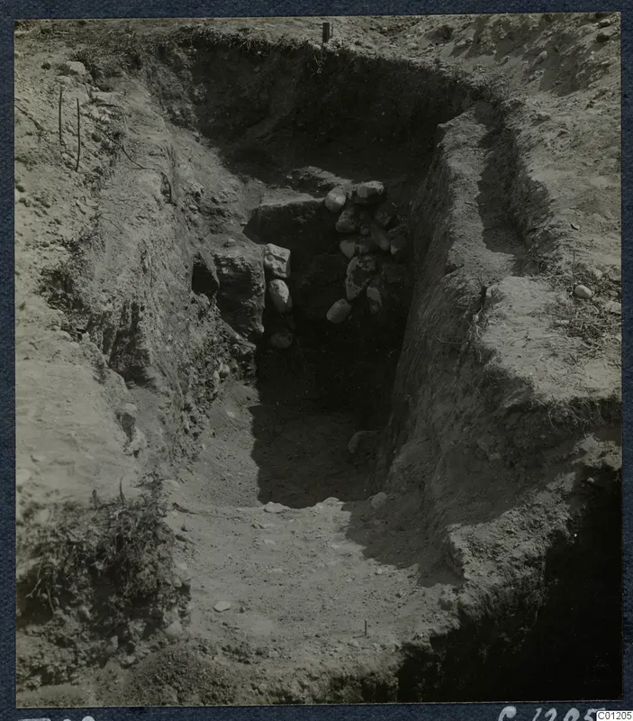 Tomb 29 at Marion during excavation, with a sloping cut leading down to a stone-filled tomb entrance