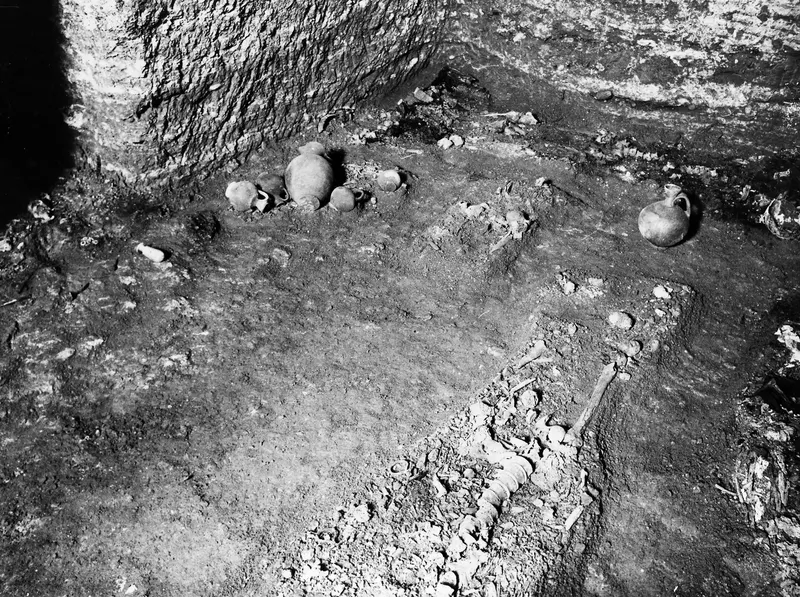 Interior of Tomb 22 at Marion, with pottery vessels on the floor and a skeleton along the lower right.