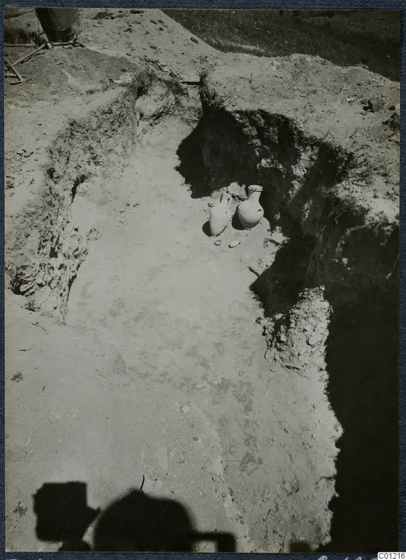 Tomb 45 at Marion: excavated cut with two pale pottery vessels standing at its far end