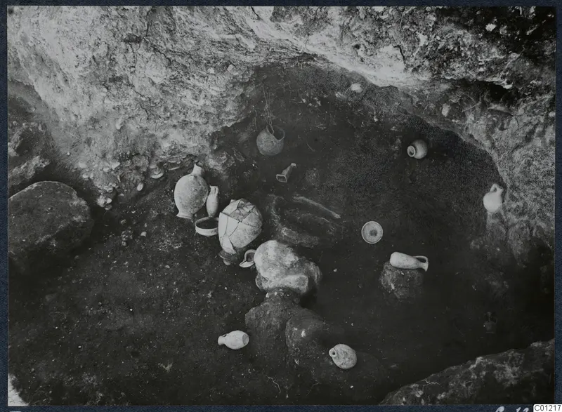 Tomb 42 at Marion during excavation, with pottery vessels and stones on the chamber floor