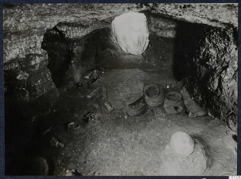 Tomb 36 at Marion during excavation, with vessels and small objects on the rock-cut chamber floor.