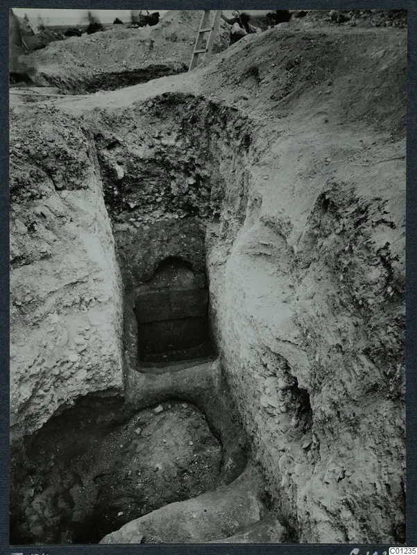 Excavated dromos leading down to an arched tomb entrance at Marion, its opening filled with stacked stone blocks.