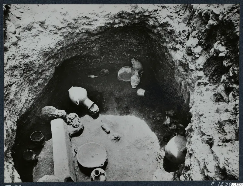 Tomb 56 at Marion during excavation, with pottery vessels and stones lying on the floor of the cut.