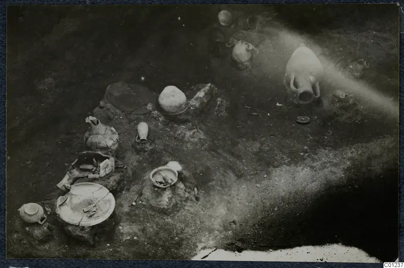 Tomb 43 at Marion, excavated floor with pottery vessels and stones lying in the soil